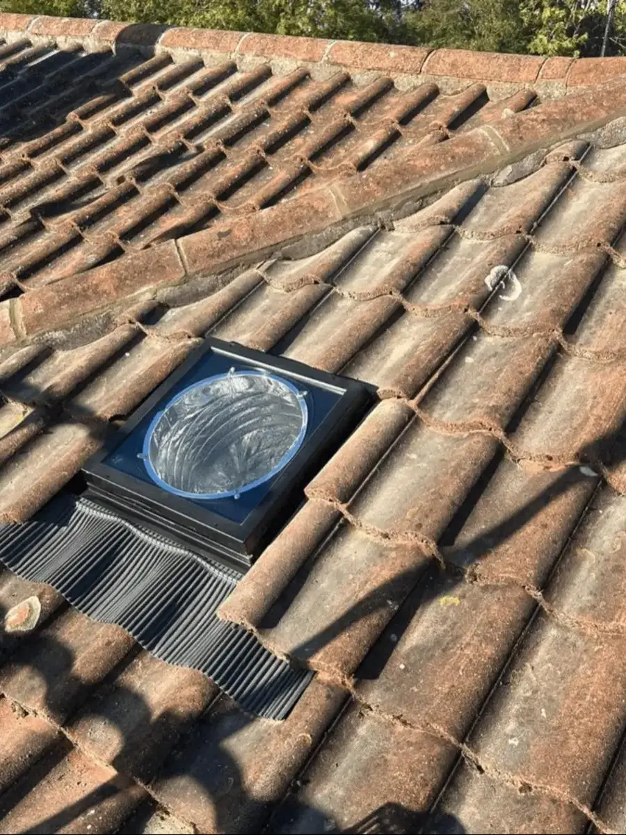 Tubular sun tunnel rooflight with weatherproof flashing fitted among existing roof tiles. By Norfolk Exterior Solutions.